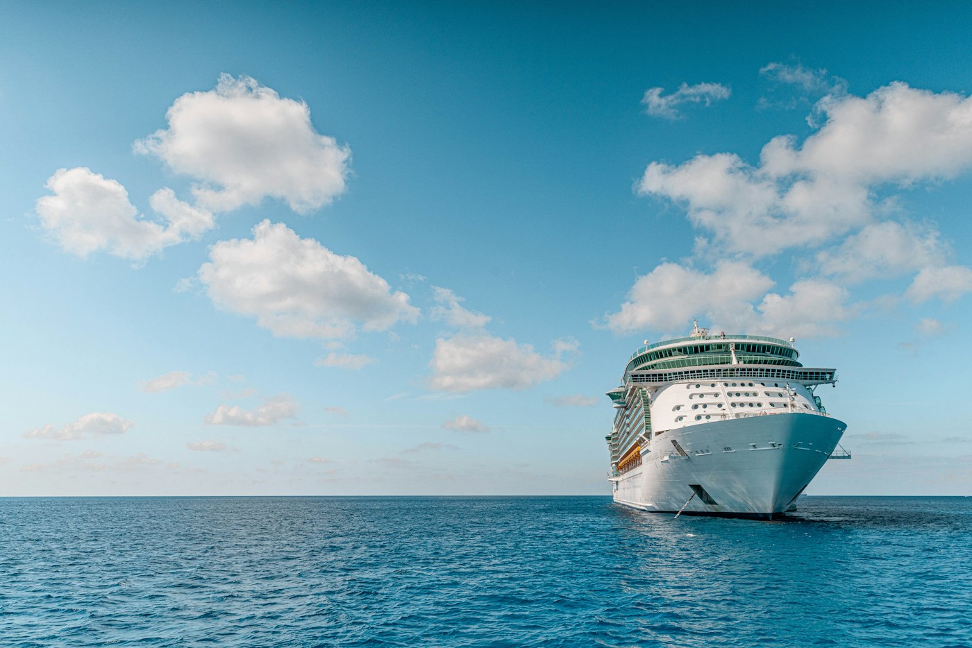 A cruise ship sailing on blue water beneath a sunny sky
